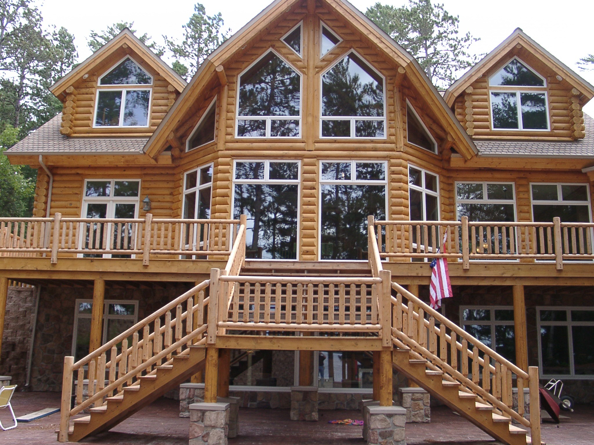 exterior of a modern log cabin with bay windows and natural log staircase
