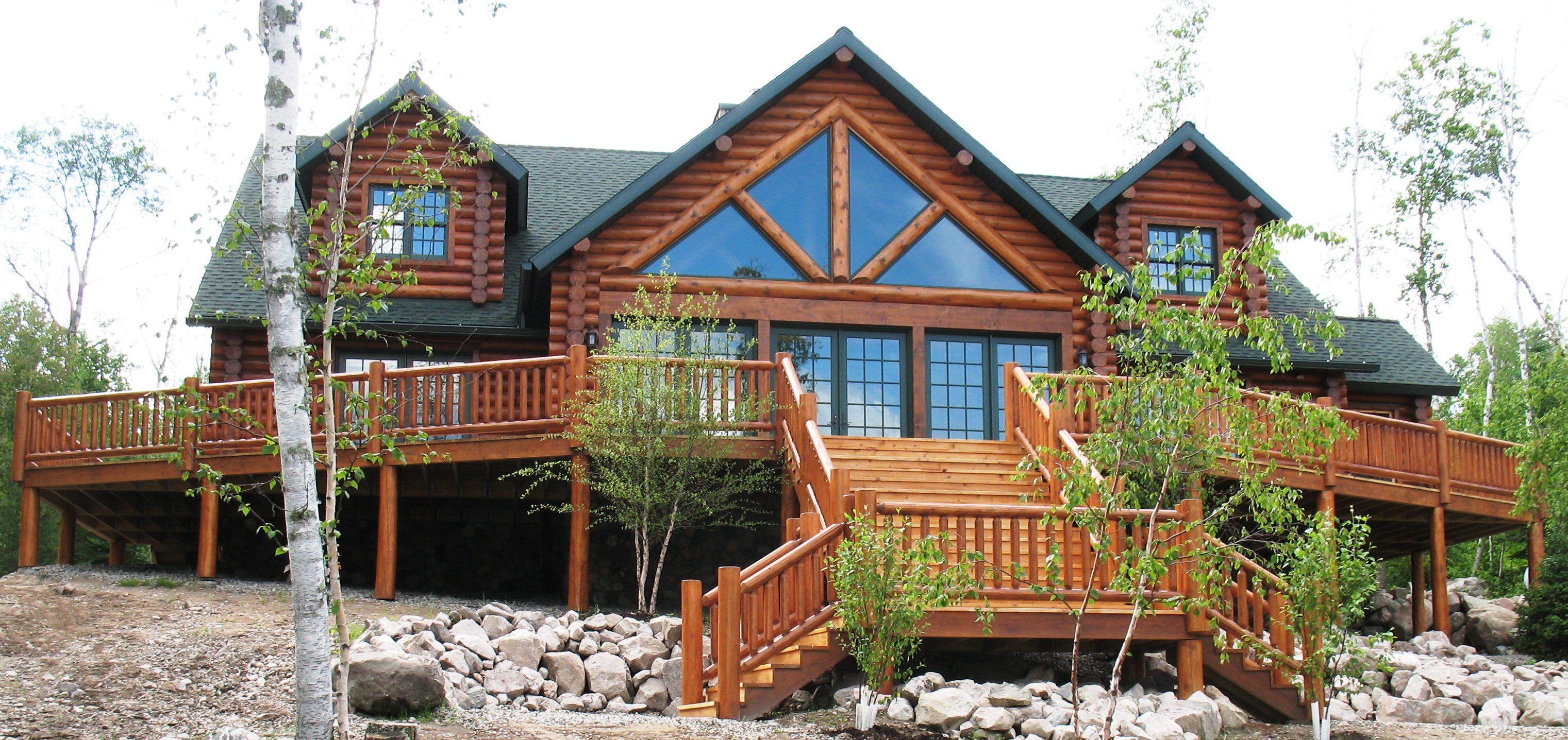 rustic | Log cabin exterior with large wooden deck and grand staircase | Outdoor stair railings